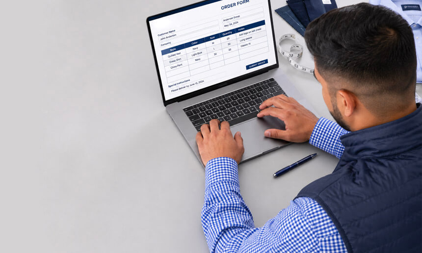 Hombre llenando un formulario de pedido en una laptop, con cinta métrica y bolígrafo sobre el escritorio