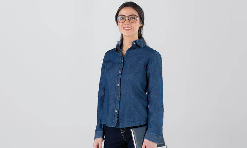 Mujer con lentes y camisa de mezclilla azul oscuro sobre fondo gris